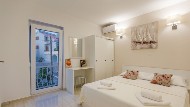 Un dormitorio con una cama, un escritorio, una silla, un armario, un espejo y un cuadro en la pared.