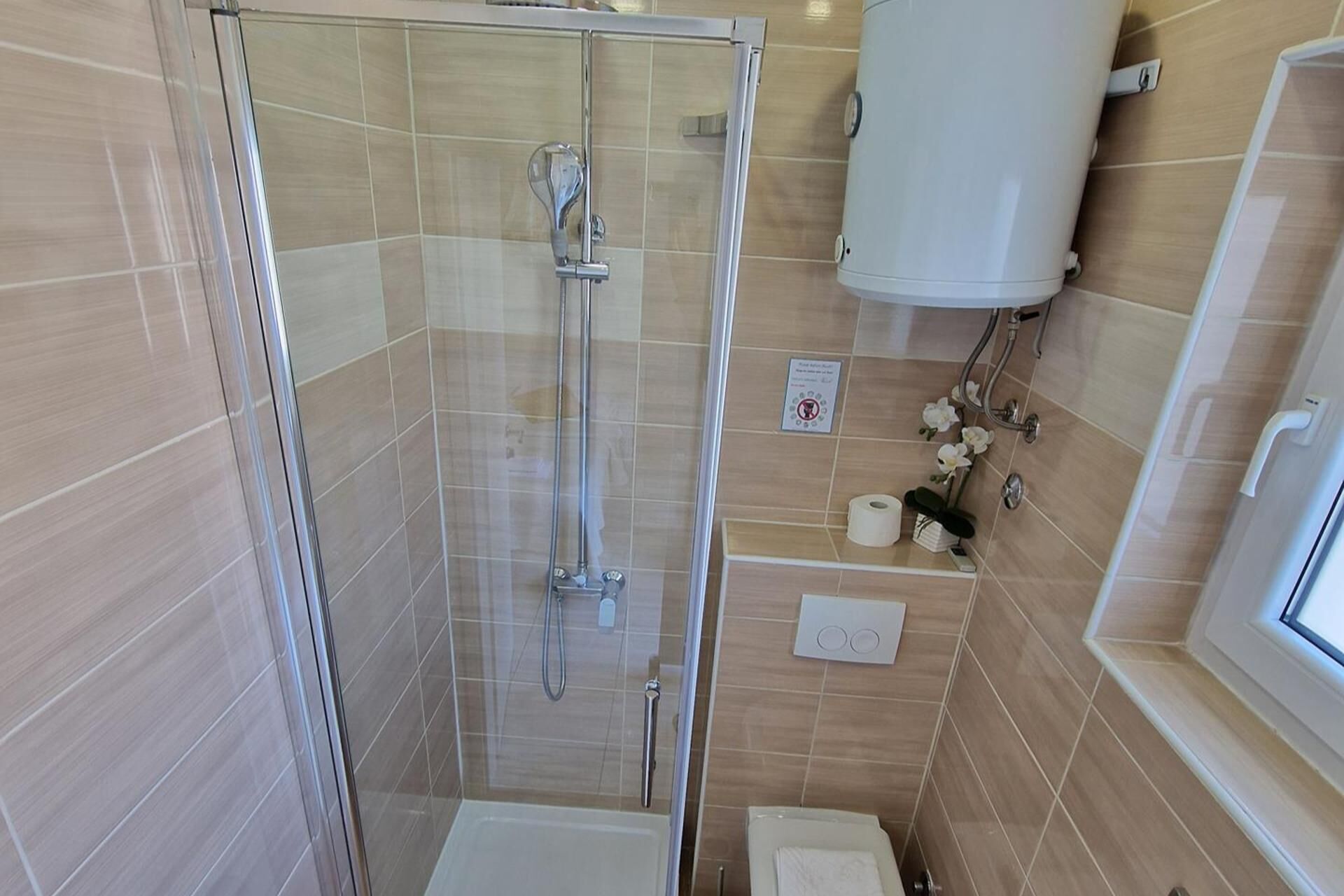 Un baño con ducha de vidrio, inodoro y lavamanos con toallero.