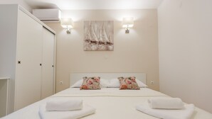 Habitación de hotel con cama, dos almohadas, un cuadro en la pared y dos lámparas de pared.