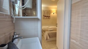 Un baño con lavabo, toalla y cabezal de ducha.