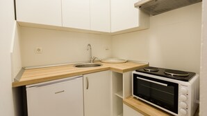 Eine kompakte Küche mit Spüle, Mikrowelle und kleinem Kühlschrank.