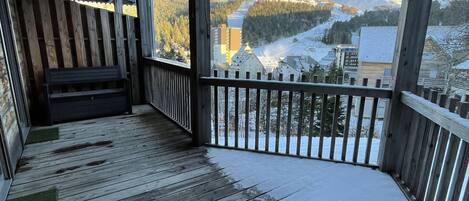 Una terraza de madera con vistas a montañas nevadas y un cielo despejado.