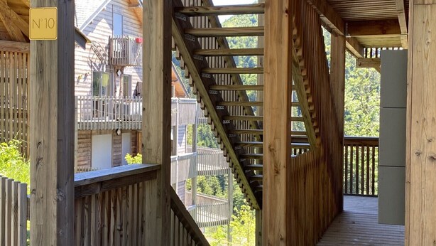 Une structure en bois sur laquelle est apposée une enseigne indiquant « Résidence L’Aiguillon », et un escalier menant à un niveau supérieur.
