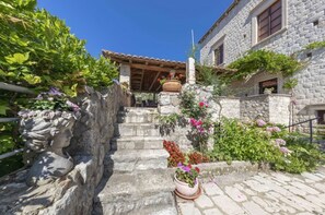 Un bâtiment en pierre avec un toit en tuiles, un escalier en pierre et des plantes en pot.