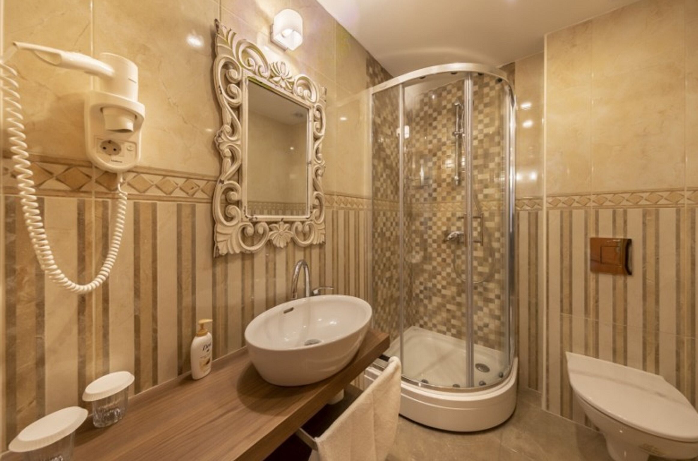 Une salle de bain comprenant un meuble-lavabo, un lavabo, un miroir, un espace douche et des toilettes.