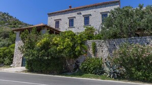 A stone building with a tiled roof, surrounded by greenery and a stone wall. - Villa Gradi (Dubrovnik)