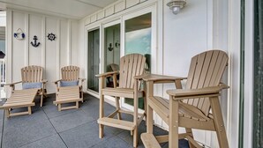 Un espace extérieur abrité, aménagé avec des chaises Adirondack en bois et une petite table, et agrémenté de décorations murales sur le thème de la marine.