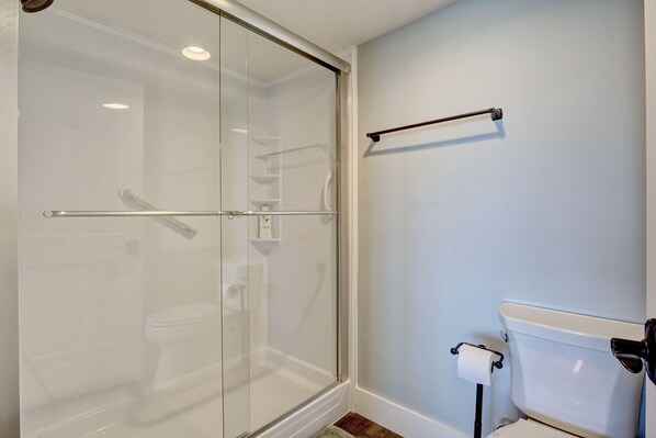 Een badkamer met een douchecabine van glas, een toilet en een handdoekrek.