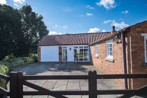 Una casa de ladrillo con techo de tejas, puerta de garaje blanca y entrada con portón.
