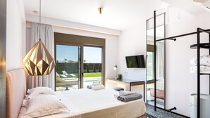 Een moderne hotelkamer met een groot bed, een bureau met een flatscreen-televisie en een balkon met uitzicht op de omgeving.