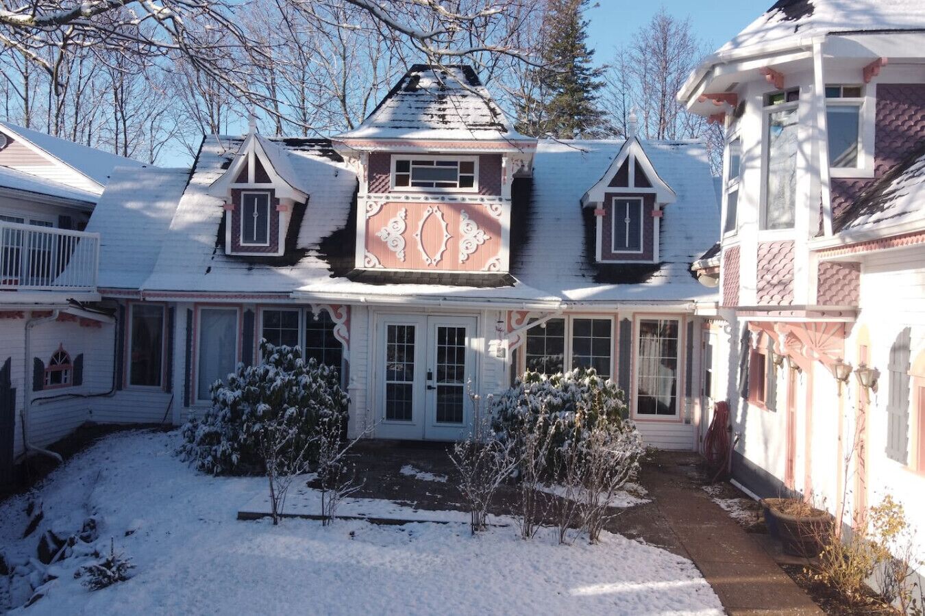 A large, multi-story house with a symmetrical facade, a central entrance with a decorative arch, and a snow-covered yard.