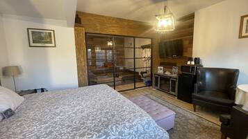 A bedroom with a large bed, a chair, a desk, and a television.