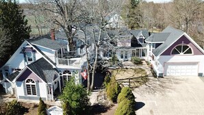 A large, multi-story house with a prominent balcony, a garage, and a driveway. - Country Suite - Private HotTub, KingBd, Downtown (Wolfville)