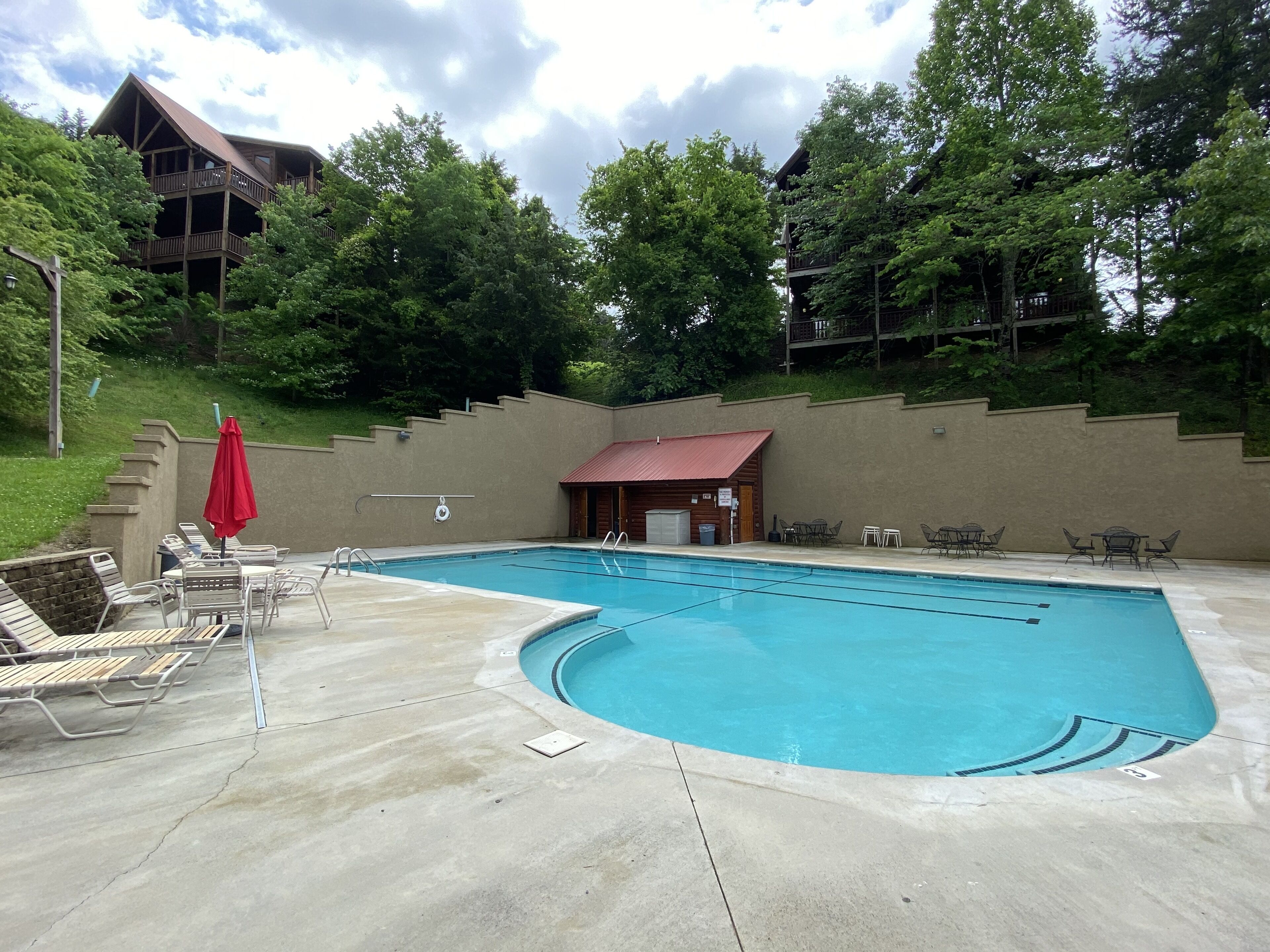 A swimming pool with lounge chairs and a small building with a red roof.