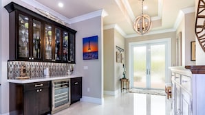 Een moderne keuken met donkere kastjes, een bar met glazen vitrage en een groot raam met uitzicht op de omgeving.