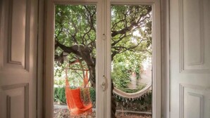 A doorway with a view of a hammock hanging between two trees. - Coimbra Guesthouse (Coimbra)