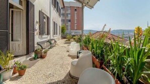 A rooftop terrace with outdoor seating, potted plants, and a view of the cityscape. - Coimbra Guesthouse (Coimbra)