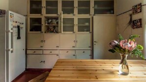 A kitchen with wooden cabinets, a wooden table, and a vase with flowers. - Coimbra Guesthouse (Coimbra)