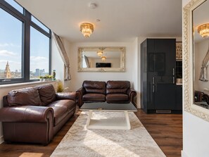 A modern living room with a leather sofa, a coffee table, and a large mirror. - 2 Bedroom Central Apartment  (Liverpool)