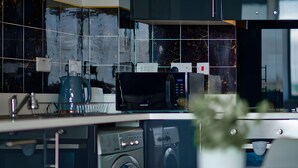 A modern kitchen with a washing machine, microwave, and a coffee maker.