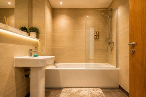 Executive appartement | Badkamer | Een bad/douchecombinatie, milieuvriendelijke toiletartikelen