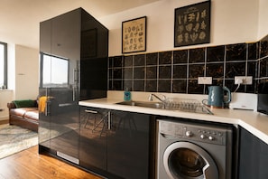Una cocina moderna con lavadora y secadora integradas, un lavabo y un ventanal.