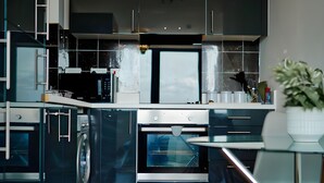 A modern kitchen with stainless steel appliances, a built-in oven, and a wooden floor.