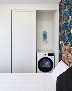 Een hotelkamer met een witte kast, een wasmachine en een wand met bloemenprint.