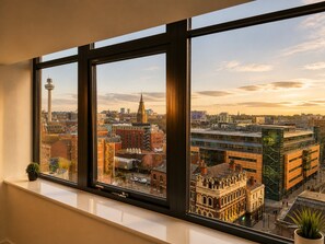 A window with a view of a cityscape, including a tower and various buildings.