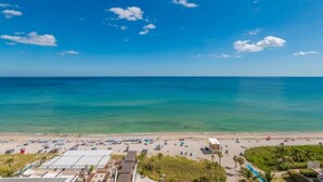 A beach with clear blue water, a sandy shore, and a few buildings in the background. - Hyde Side Ocean View 1 Bedroom Condo by RedAwning (Hollywood)