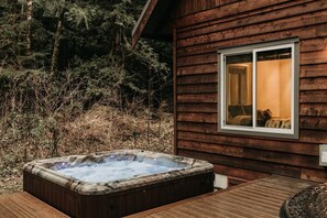 Eine Holzhütte mit Whirlpool und einem Fenster mit Blick auf einen Wald.
