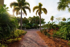 Stroll through the lush garden, lined with palm trees and shrubs, to the entrance of this serene oasis.