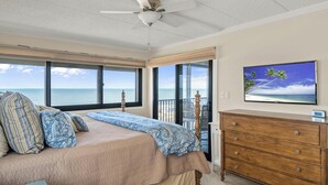 A bedroom with a bed, a dresser, a ceiling fan, and a TV displaying a beach scene. - Oceana 1-Upgraded 2 Bedroom Ocean Front Oceana Condo with Outdoor Pool! (Ocean City)