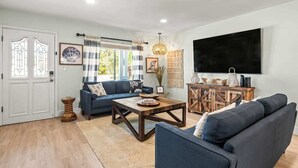 Ein Wohnzimmer mit einer Couch, einem Couchtisch und einem an der Wand befestigten Fernseher.