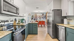Eine moderne Küche mit Mikrowelle, Herd und Kühlschrank. Ein Essbereich mit Tisch und Stühlen ist ebenfalls vorhanden.