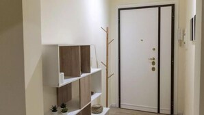 A hallway with a white door, wooden shelves, and a small plant. - Via delle Medaglie d'Oro (Rome)
