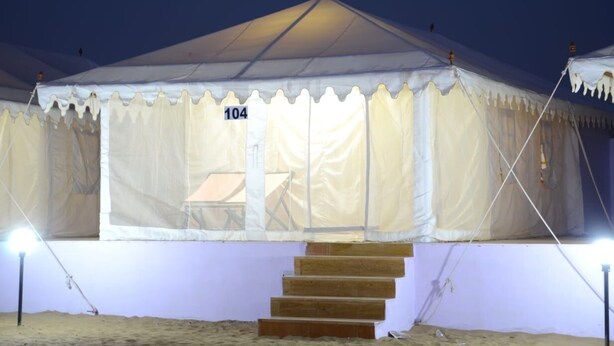 A tent with a number '104' on it, a staircase leading up to the entrance, and a light source on the left. - Ozaki Desert Camp Jaisalmer  (Jaisalmer)