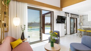 Un salon moderne avec un canapé, une table ronde ornée d’un vase, et une vue sur une piscine grâce à de grandes portes coulissantes.