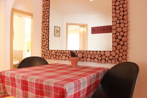 A dining area with a checkered tablecloth, a potted plant, and a wall-mounted log display. - Winter dream vacation apartment in the Zillertal in direct proximity to the Horbergbahn ski lift (Schwendau)
