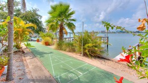 A green outdoor shuffleboard court with a view of a waterfront and a wooden dock. - Front-Row Waterfront Escape – 1BR Condo on Clearwater Beach (Clearwater Beach)