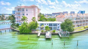 A waterfront hotel with a dock, lush greenery, and a cityscape in the background. - Front-Row Waterfront Escape – 1BR Condo on Clearwater Beach (Clearwater Beach)
