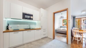 A modern kitchen with white cabinets, a Bosch microwave, and a wooden countertop. - Apartamenty Sun & Snow Nautikka Park (Krynica Morska)