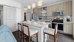 A modern kitchen with a central island, stainless steel appliances, and pendant lighting.