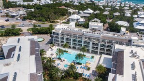 A resort with a large pool, multiple floors, and a view of the ocean.