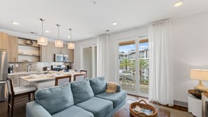 A modern living room with a sofa, dining table, and kitchen area.