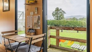 Una habitación con un banco de madera y vistas a un campo verde a través de una ventana.
