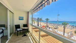 A balcony with a view of a beach, a dining area with chairs, and a painting on the wall. - GEMELOS 1 MODERN SEAVIEWS R084 (Benidorm)