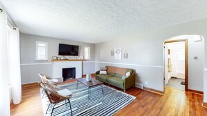 A living room with a fireplace, a television, a sofa, and a dining table. - Home of Champions: HOF Village Comfort (Canton)