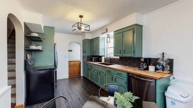 A modern kitchen with green cabinets, a black refrigerator, a microwave, and a coffee maker. - Home of Champions: HOF Village Comfort (Canton)