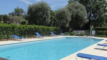 A swimming pool with blue lounge chairs and a tiled deck.
